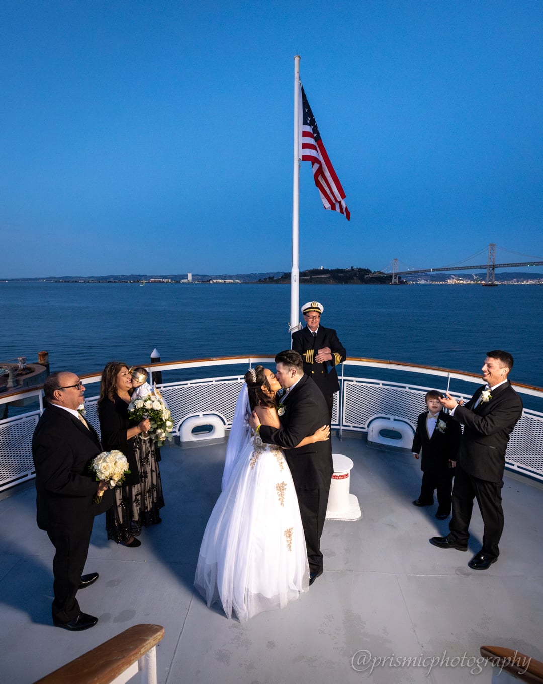 A couple kisses in their wedding ceremony board the Hornblower boat